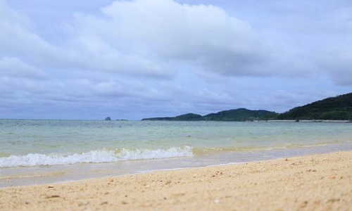 曇り空の下に広がる沖縄のビーチ。晴天のイメージとは異なるリアルな空模様